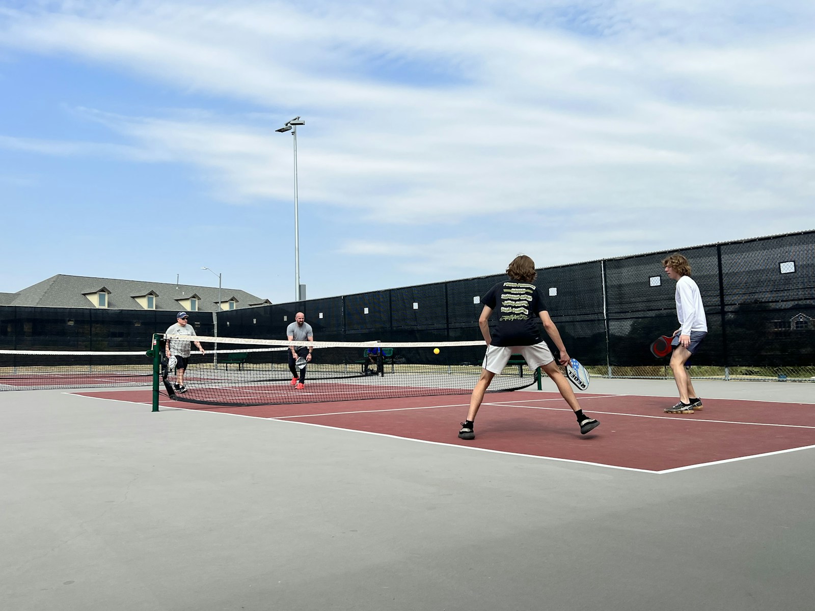 Four adults playing doubles pickleball outdoors